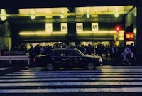 a black car in front of a crowd of people