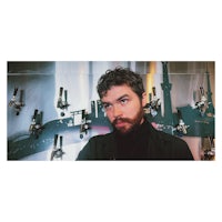 a man with a beard standing in front of a wall of beer taps