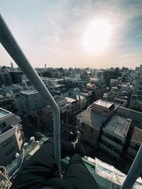 a person sitting on a railing overlooking a city
